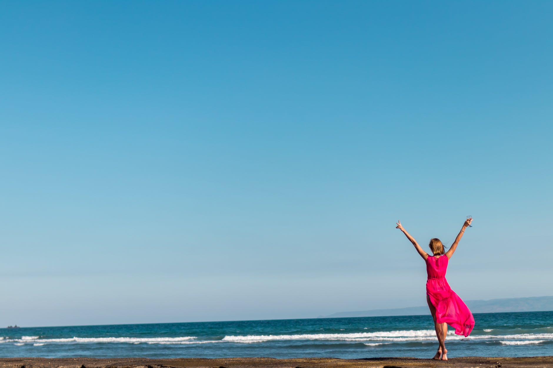 woman wearing pink dress standing on shore