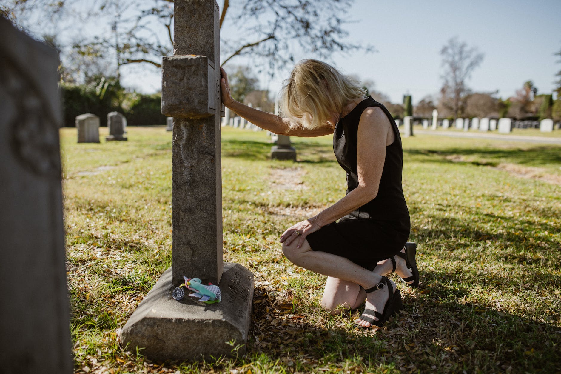 photo of woman kneeling in front of gravestone