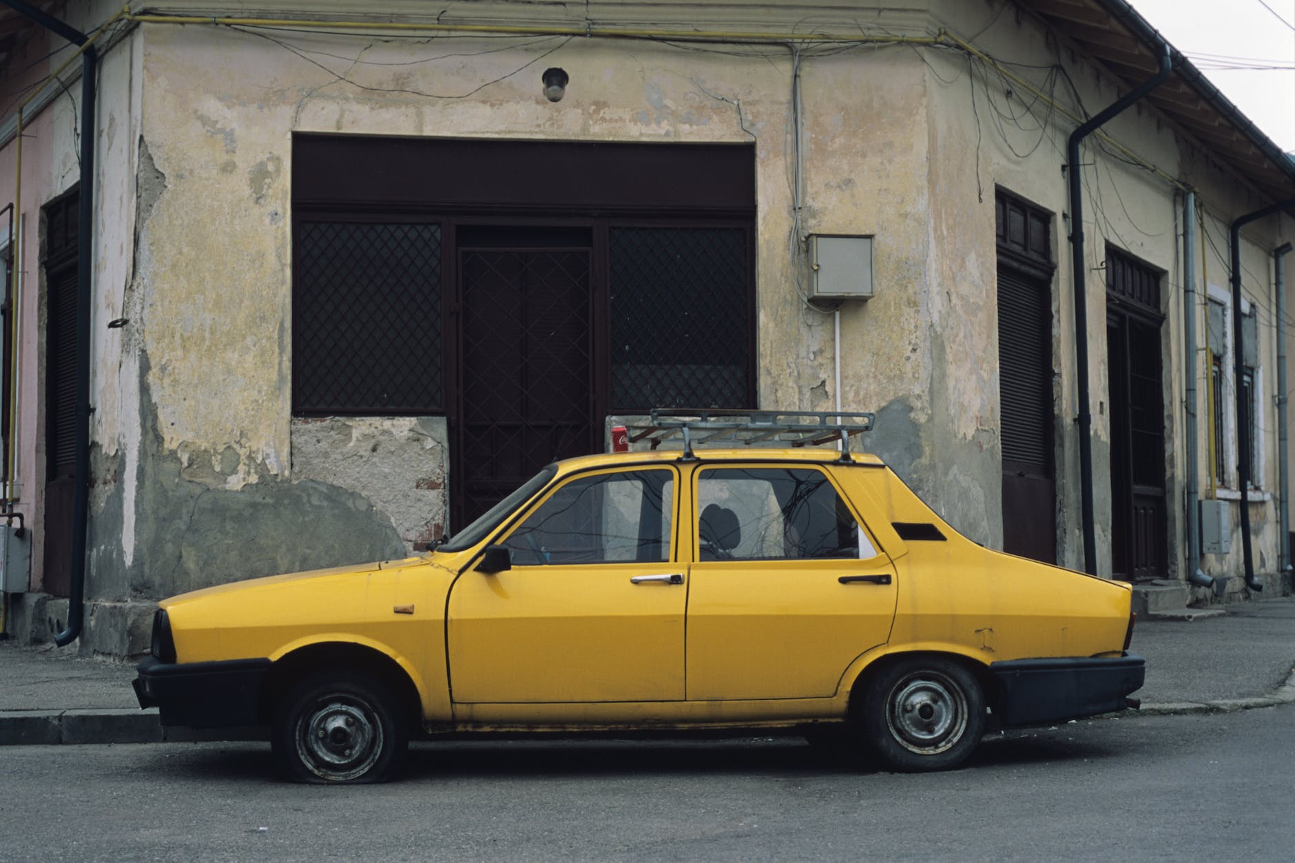 yellow car parked beside an abandoned building