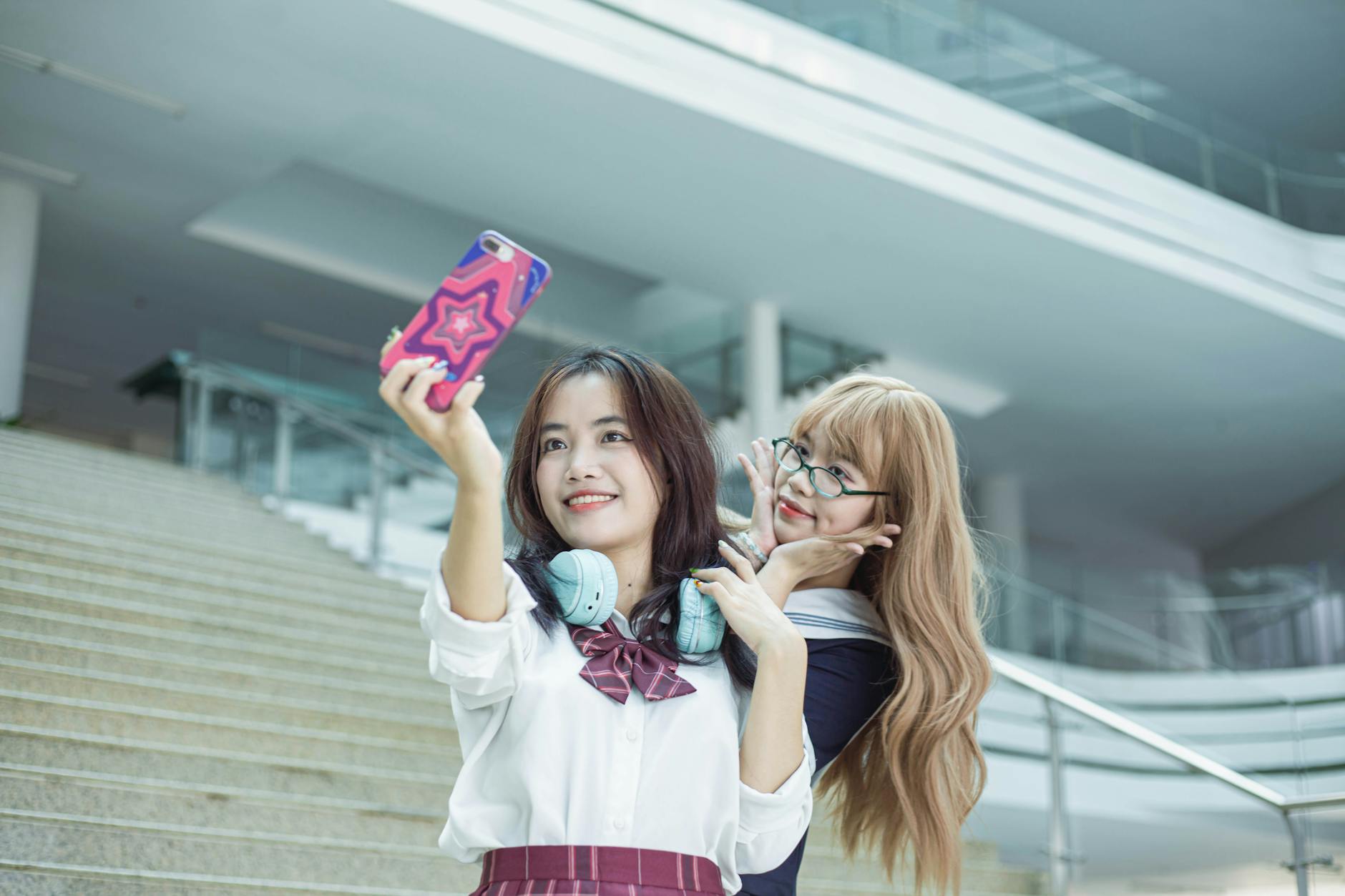 two girls taking a photo together in from of the school stairs