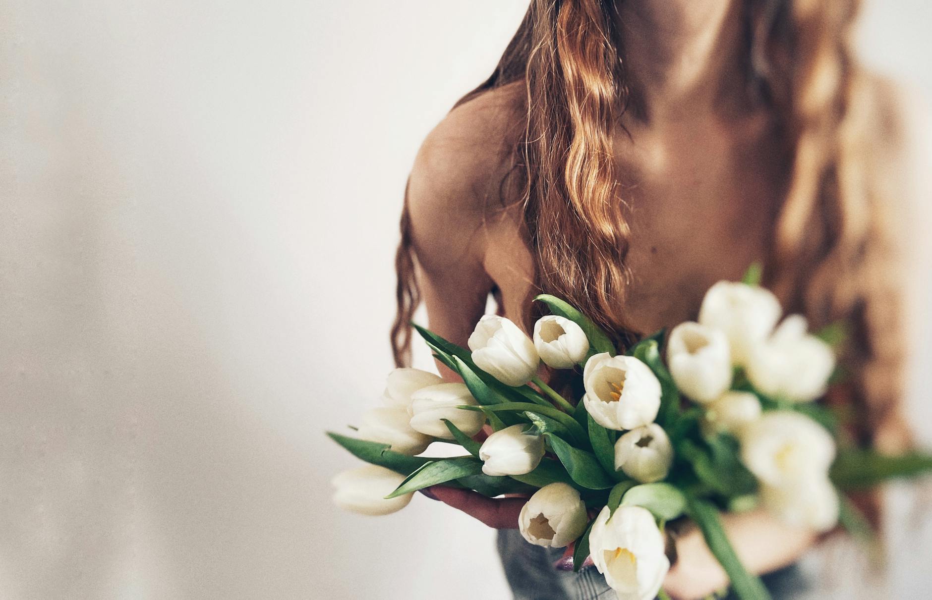 woman holding bouquet of white tulips indoors